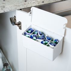 a white box filled with lots of blue and green marbles on top of a counter