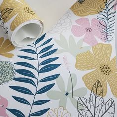 a wallpaper with colorful flowers and leaves on white paper, next to a roll of tape