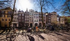 many bicycles are parked in front of some buildings on a sunny day with the sun shining