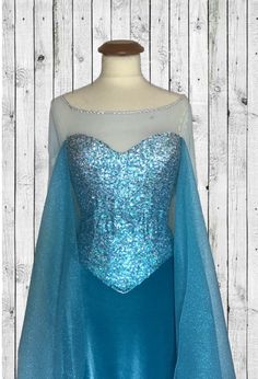 a dress on a mannequin with blue sequins and an aqua cape