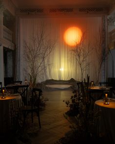 a dimly lit room with tables, chairs and candles on the table in front of an open window