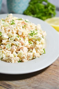 a white plate topped with chicken salad on top of a wooden table