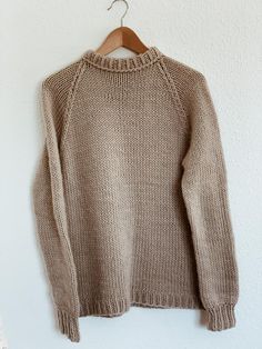 a brown sweater hanging on a white wall