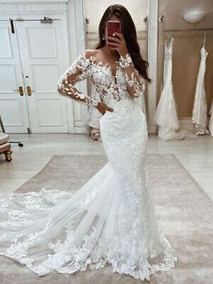 a woman in a wedding dress taking a selfie with her cell phone while standing in front of a mirror