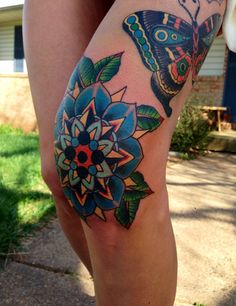 a woman's leg with a butterfly and flower tattoo on the side of her thigh