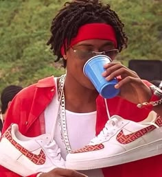 a woman drinking from a blue cup while sitting on top of a white tennis shoe