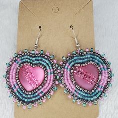 a pair of pink and blue beaded heart shaped earrings on top of a card