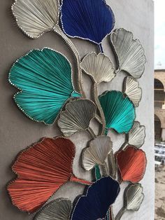 a metal wall hanging with many different colored seashells attached to the side of it