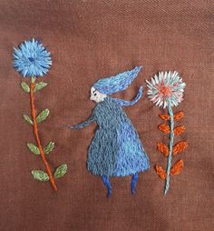 an embroidered image of a blue fairy holding a flower