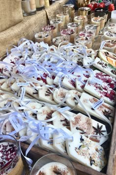 many different types of soaps on display at a market table with candles and other items