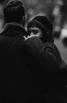 a man and woman walking down the street talking on their cell phones while holding each other's hands