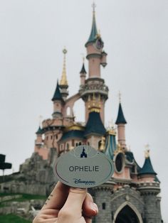 a person holding up a sticker in front of a castle with the name ophelie on it