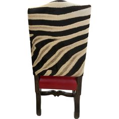 a chair with a zebra print cover on it's back and red leather seat