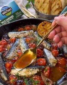 someone is spooning some kind of food in a pan with other foods on the table