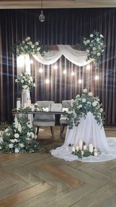 a wedding ceremony setup with white flowers and greenery on the table, surrounded by candles