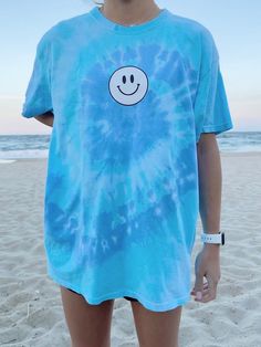 Black & white smiley face screen printed onto a Gildan t-shirt. The tie dye color is blue and purple and it is called "wildflower". This fun tee is perfect to throw over your bathing suit on a beach day. ✰ MODEL INFO: ✰ Height: 5'4" Size: normally wears a small, but is modeling a large for an oversized look. ★ MATERIAL: ★ 50% cotton, 50% polyester Tie Dye Retro Smiley Face T-Shirt, Summer Tee, Gift for Her, Trendy Aesthetic Happy Smile T-Shirt Preppy Shirts Simply Cute Tees, Cheap Trendy T-shirt With Rainbow Print, Cheap Summer T-shirt With Rainbow Print, Cheap Spring T-shirt With Splicing, Cheap Trendy Shirt For Spring, Cheap Cute Easter Tops, Preppy Shirt Cheap, Cheap Cute Summer T-shirt, Cheap Tie Dye Tops For The Beach