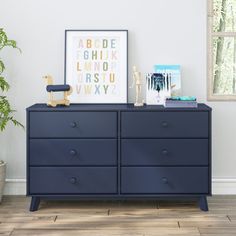 an empty room with a blue dresser and potted plant