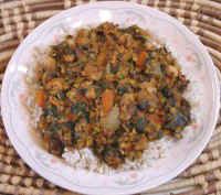 a white plate topped with rice and vegetables on top of a woven table cloth next to a basket