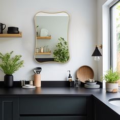 a kitchen with black counter tops and wooden shelves filled with pots, pans, and plants