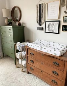 a baby's crib and dresser in a room with pictures on the wall