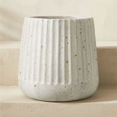 a white vase sitting on top of a counter next to a window sill with gold speckles