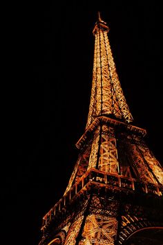 the eiffel tower lit up at night with lights on it's sides