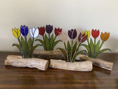 three wooden pieces with flowers on them sitting on a table next to a piece of driftwood