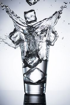 water splashing into a glass with ice cubes