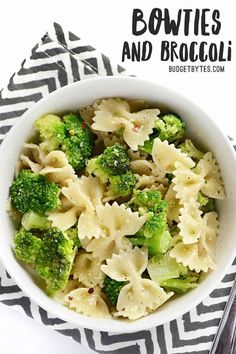 a white bowl filled with pasta and broccoli on top of a black and white napkin