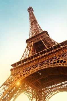 the eiffel tower in paris is lit up at sunset, with bright sunlight coming from behind it