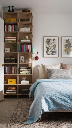 a bedroom with a bed, bookshelf and pictures on the wall