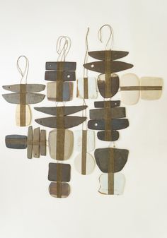 a group of knives hanging from strings on a white wall next to another piece of wood