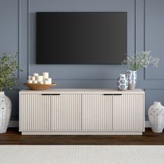 a living room scene with focus on the tv and vases in front of it