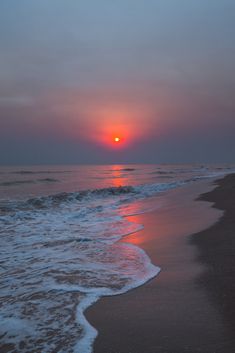 the sun is setting over the ocean with waves