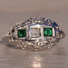 The 132nd Avenue: Antique Filigree Diamond And Emerald Ring In White Gold. The Ring Centers On An Old Cut Natural Diamond Inside A Square Box Finished With Very Fine Milgrain. On Either Side Of The Center Is A Carre Cut Lab-Grown Emerald With A Deep Very Slightly Bluish-Green Color In A Finely Milgrained Bezel. An Intricate Filigree Pattern Exists Throughout The Top Of The Ring Into The Through-Finger View And Shank. The Ring Is Crafted In 14 Karat White Gold And Is Currently A Finger Size 3.25 Yet Can Be Adjusted To Any Finger Size For An Additional Charge On Request. Diamond And Emerald Ring, Antique Filigree, Filigree Pattern, Bluish Green, Emerald Ring, Vintage Diamond, Womens Jewelry Rings, Green Color, Lab Grown