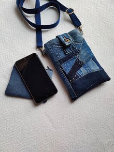 a cell phone is laying next to an old pair of jeans and a blue strap