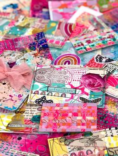 many different colored papers with bows and designs on them, all piled up in the same pile