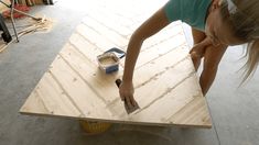 a woman is working on a piece of plywood