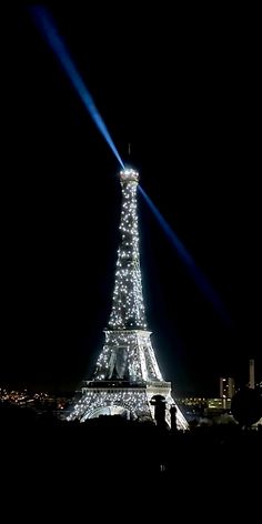 the eiffel tower is lit up at night with lights on it's sides