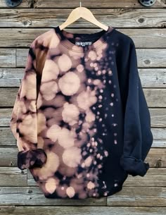 a black and pink sweatshirt hanging on a wooden wall