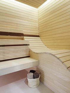 a white bucket sitting on top of a wooden bench next to a wall covered in slats