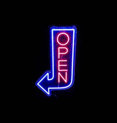 a neon sign that says open with an arrow pointing to the right and left side