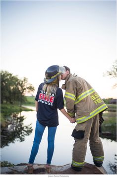 a man and woman dressed in firefighter gear standing next to each other near water