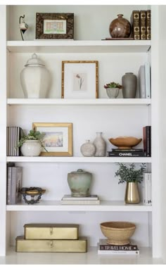 a white book shelf filled with books and vases