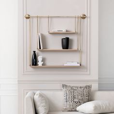 a white couch sitting next to a wall mounted shelf filled with vases and books