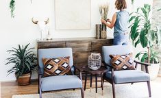 a woman standing next to two chairs in a living room