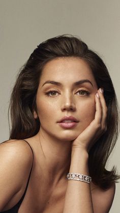 a woman with her hand on her face and wearing a bracelet, posing for the camera