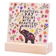 a wooden block with an elephant and flowers on it, saying a beautiful day begins with a beautiful mindset