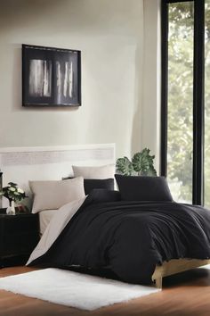 a black and white bed in a bedroom next to a window with plants on it