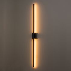 a wall light that is on the side of a wall with a long tube attached to it